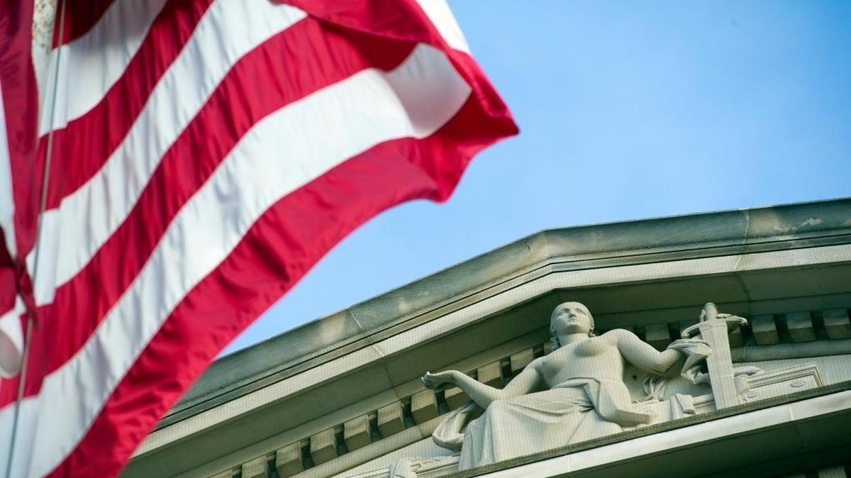 The American flag flies outside the Justice Department, where inquiries into controversies involving Hillary Clinton could become delicate matters whether she or Donald Trump becomes the president.