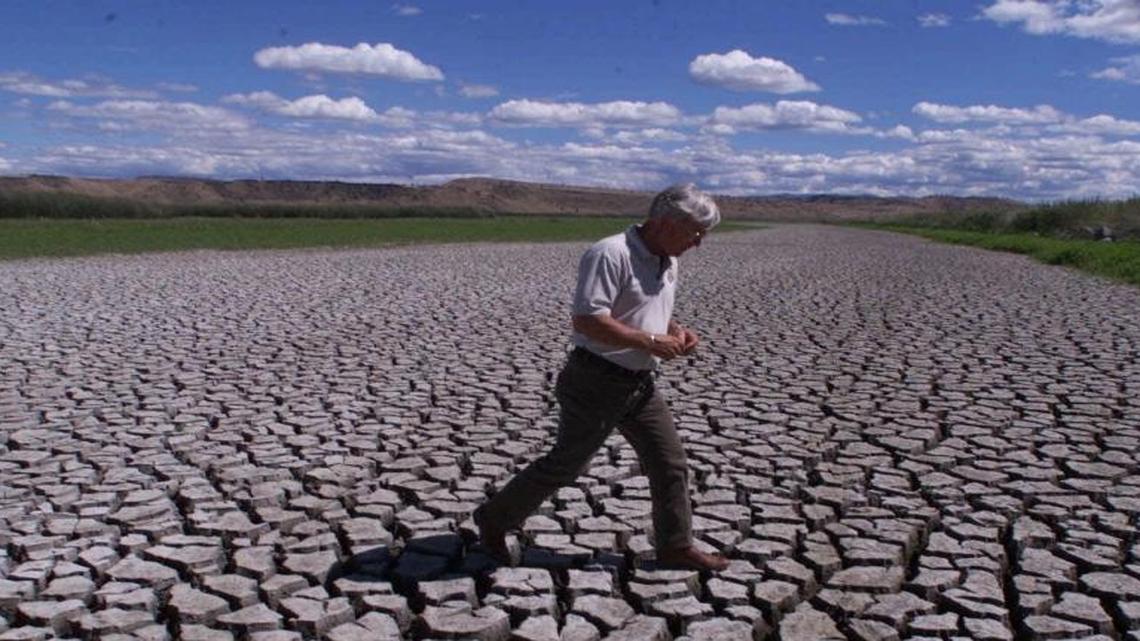 Phil Norton, manager of the Klamath Basin National Wildlife Refuges in Tulelake, Calif., on July 17, 2001, walks across the mud flats that were created when water from the Klamath River was cut off.