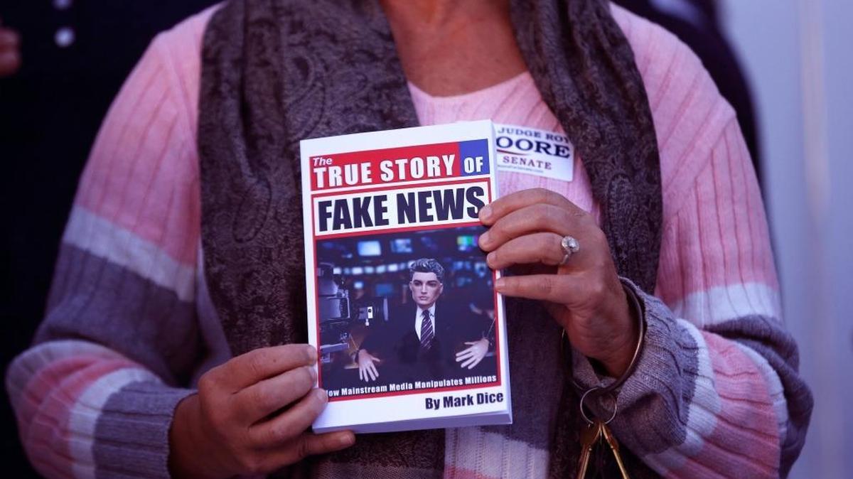 FILE- In a Nov. 17, 2017 file photo, a supporter holds up a "Fake News" book while Kayla Moore, wife of U.S. Senate candidate Roy Moore, speaks at a press conference in Montgomery, Ala. Would a story that seeks to unpack or drill down on a list of tiresome words and phrases be impactful or a nothingburger? Worse, would it just be tons of fake news? Well, dish all you want, but Northern Michigan's Lake Superior State University on Sunday released its 43rd annual List of Words Banished from the Queen's English for Misuse, Overuse and General Uselessness.(AP Photo/Brynn Anderson_File)