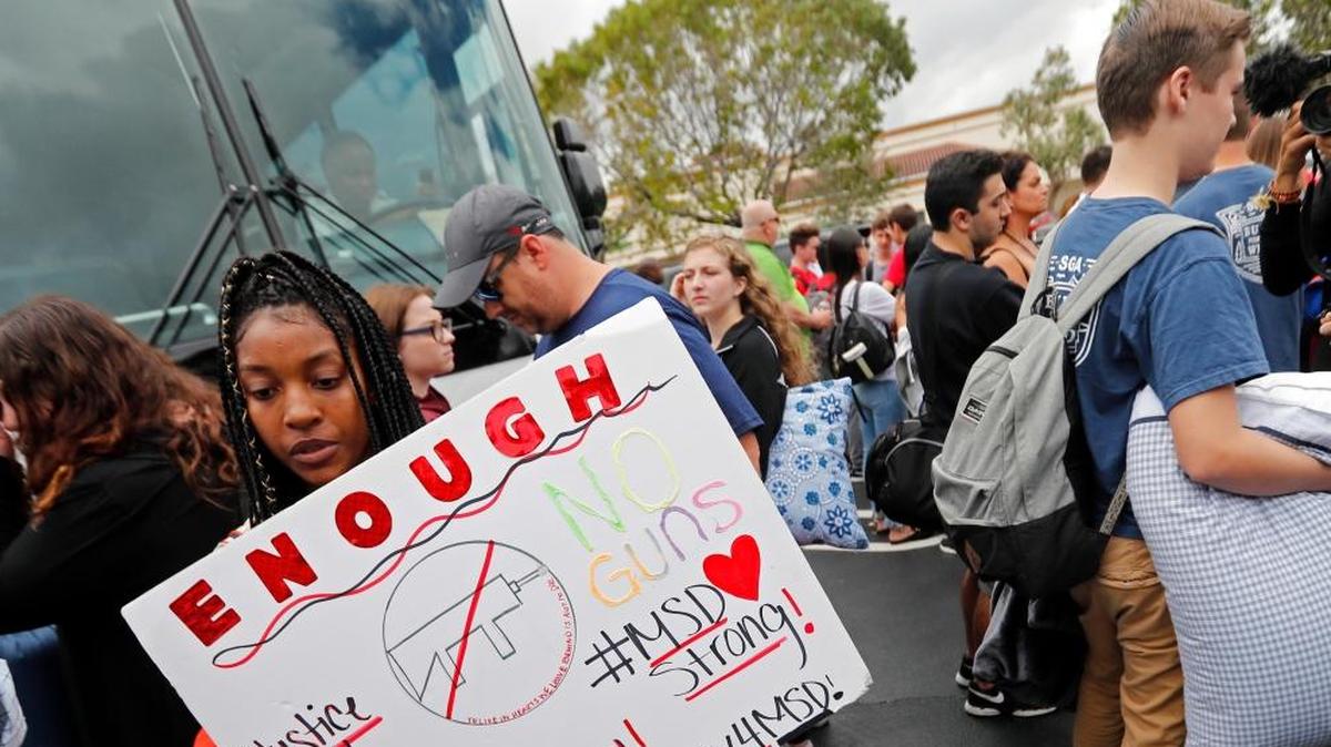 Tyra Hemans, de 19 años, a la izquierda, y Logan Locke, de 17 años, a la derecha, estudiantes que sobrevivieron al tiroteo en la Secundaria Stoneman Douglas, esperan para subir a los autobuses en Parkland, el martes 20 de febrero de 2018.