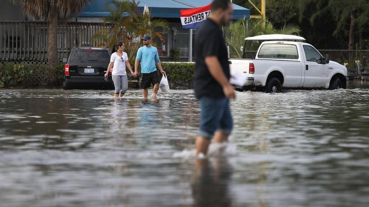 Yaneisy Duenas (L) and Ferando Sanudo walk through the flooded parking lot to their boat at the Haulover Marine Center on November 14, 2016 in North Miami, Florida. The flood waters are caused by the combination of the lunar orbit which causes seasonal high tides, also known as a King tide, and what some scientists believe is rising sea levels due to climate change.