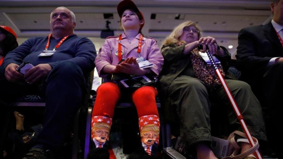 Millie March, 12, of Fairfax, Va., center, wears socks featuring President Donald Trump while awaiting his speech to the Conservative Political Action Conference (CPAC), at National Harbor, Md., Friday, Feb. 23, 2018.