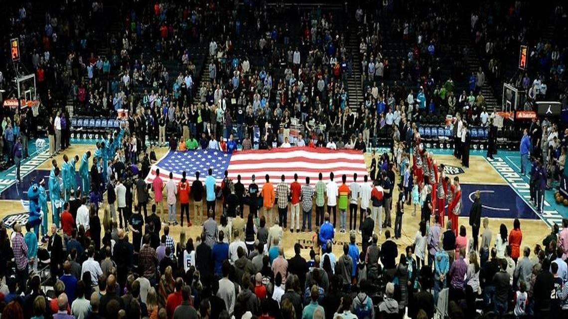 Fans and players listen to the National Anthem prior to the Charlotte Hornets vs Atlanta Hawks game at Time Warner Cable Arena in Charlotte, N.C., on Saturday, March 28, 2015. The Hornets defeated the Hawks 115-100.