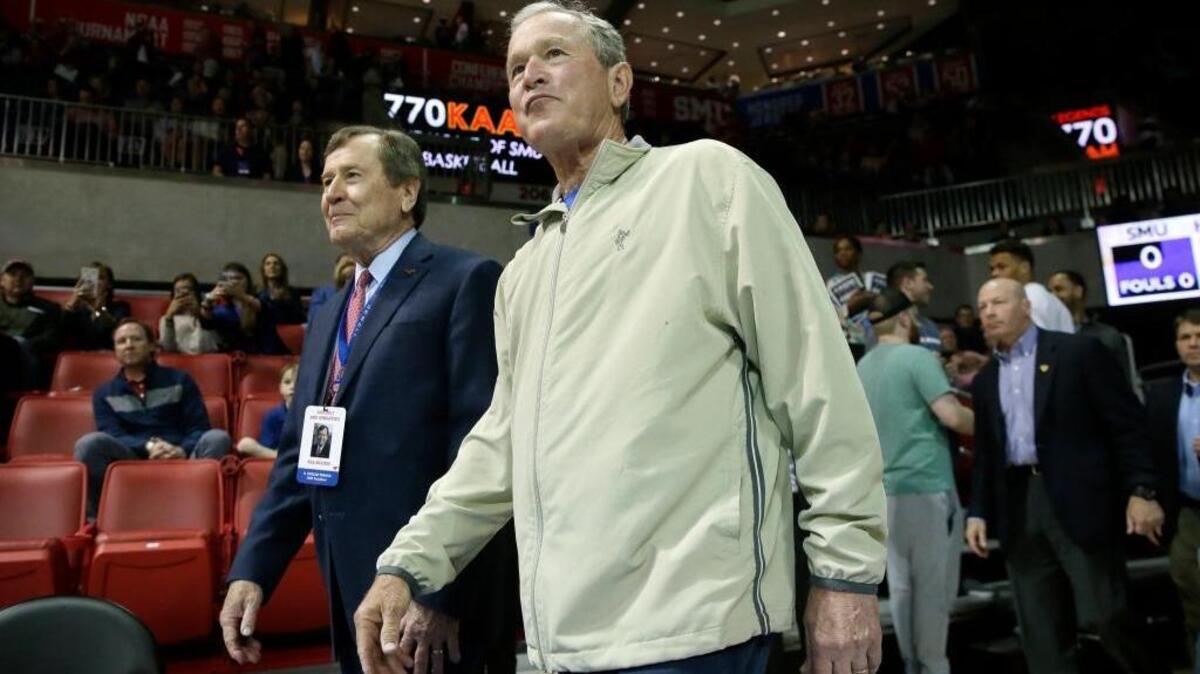 Former President George W. Bush, right, walks with SMU president R. Gerald Turner and they arrive for an NCAA college basketball game between Cincinnati and SMU in Dallas, Sunday, Feb. 12, 2017.