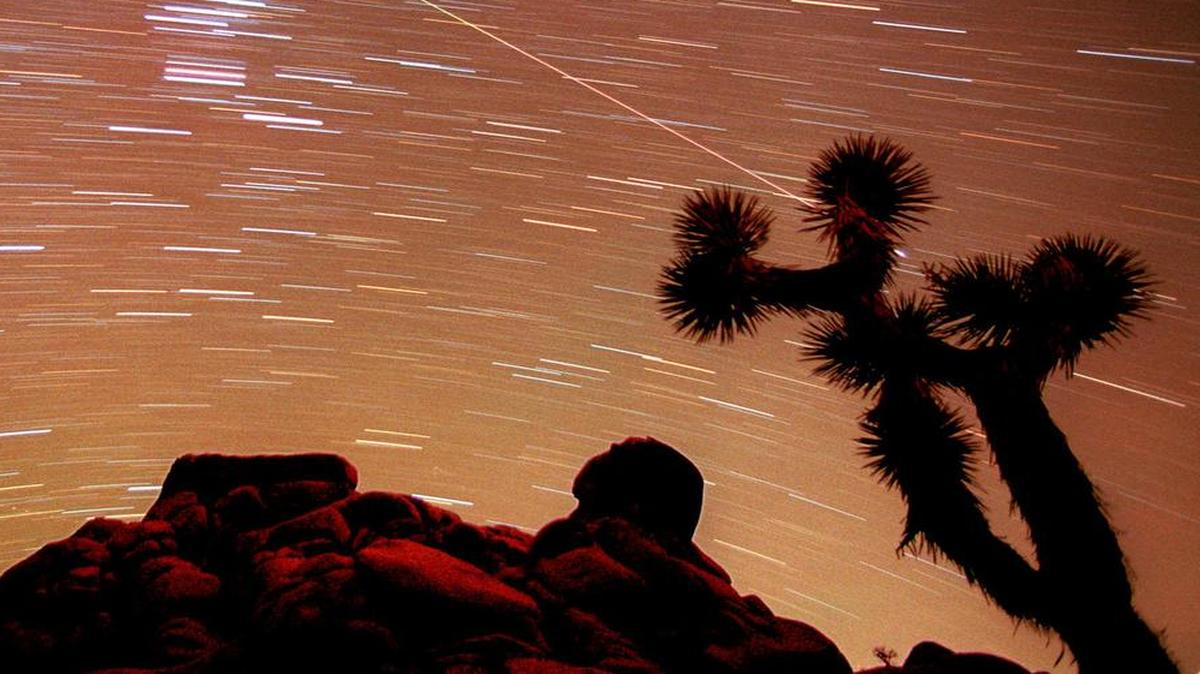 In this Nov. 17, 1998, file time exposure photo, a meteor streaks through the sky over Joshua trees and rocks in Southern California's Mojave Desert.