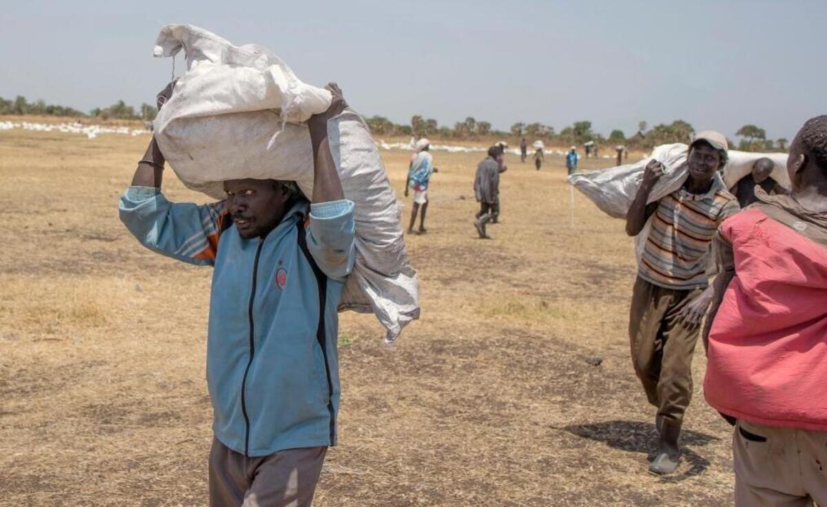 In this Monday, March 6, 2017 photo, South Sudanese men carry food distributed by the World Food Programme in Leer County Southern Leich State in South Sudan. An estimated 100,000 people are experiencing famine, and another 1 million people are on the brink of starvation, South Sudan's government and U.N. agencies said in late February. South Sudan is now Africa's largest migrant crisis as more than 3 million people have either fled the country or become internally displaced, according to the U.N.