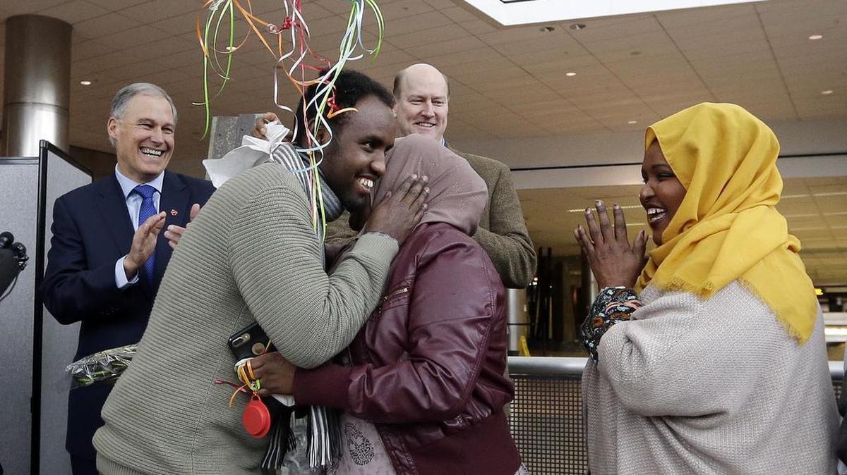 Isahaq Ahmed Rabi, second left, greets extended family members as Washington Gov. Jay Inslee, left, and Port of Seattle Commissioner President Tom Albro applaud shortly after Rabi's arrival Monday, Feb. 6, 2017, at Seattle Tacoma International Airport in SeaTac, Wash. Rabi was blocked from entry to the U.S. last week due to President Donald Trump's immigration order. Rabi is a citizen of Somalia. His wife is a U.S. citizen.