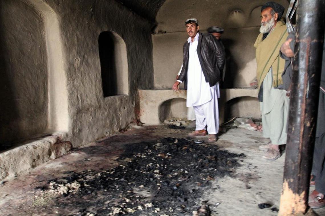 Men stand next to blood stains and charred remains inside a home where witnesses say Afghans were killed by a U.S. soldier in Panjwai, Kandahar province south of Kabul, Afghanistan in 2012