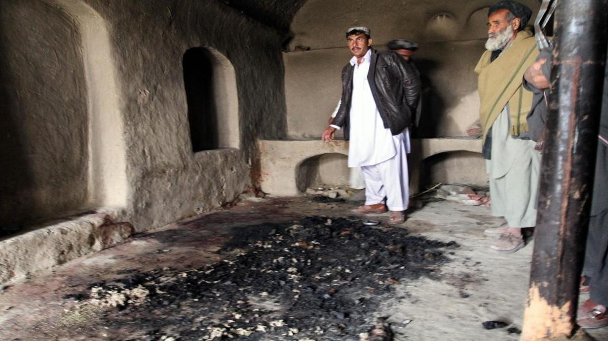 Men stand next to blood stains and charred remains inside a home where witnesses say Afghans were killed by a U.S. soldier in Panjwai, Kandahar province south of Kabul, Afghanistan in 2012