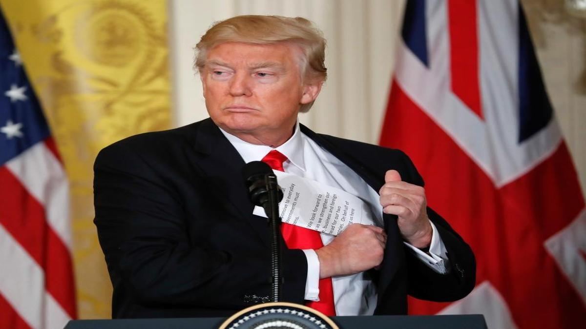 President Donald Trump tucks away his notes near the conclusion of a joint news conference with British Prime Minister Theresa May in the East Room of the White House White House in Washington, Friday, Jan. 27, 2017.