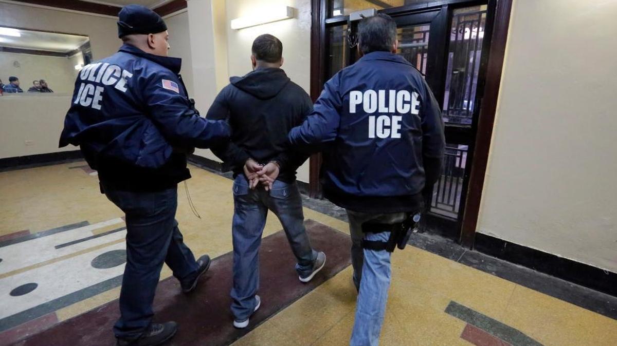 In this March 3, 2015 photo, Immigration and Customs Enforcement officers escort an arrestee in an apartment building, in the Bronx borough of New York, during a series of early-morning raids. New York City leaders are trying to strike a balance between purging dangerous criminals and protecting some of its roughly 500,000 undocumented immigrants.