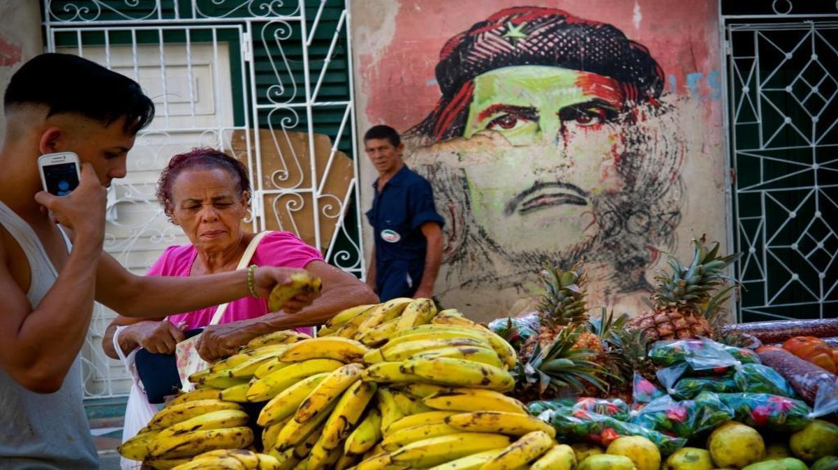 A fruit vendor attends to a client backdropped by a mural of Che Guevara, in Old Havana, Cuba, Saturday, March 19, 2016. President Barack Obama will visit the island on March 20. During his three-day trip, the first to the country by a sitting U.S. president in nearly 90 years, he will meet with President Raul Castro at the Palace of the Revolution and attend an exhibition baseball game.