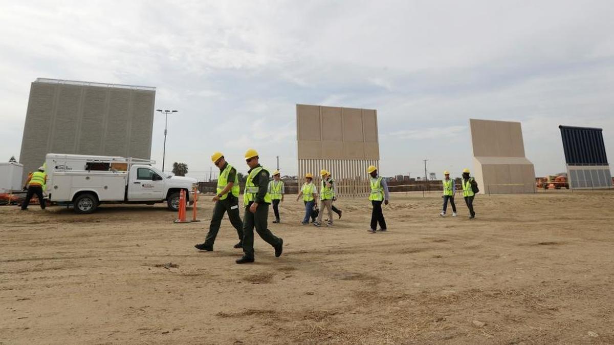 People pass border wall prototypes as they stand near the border with Tijuana, Mexico in San Diego.