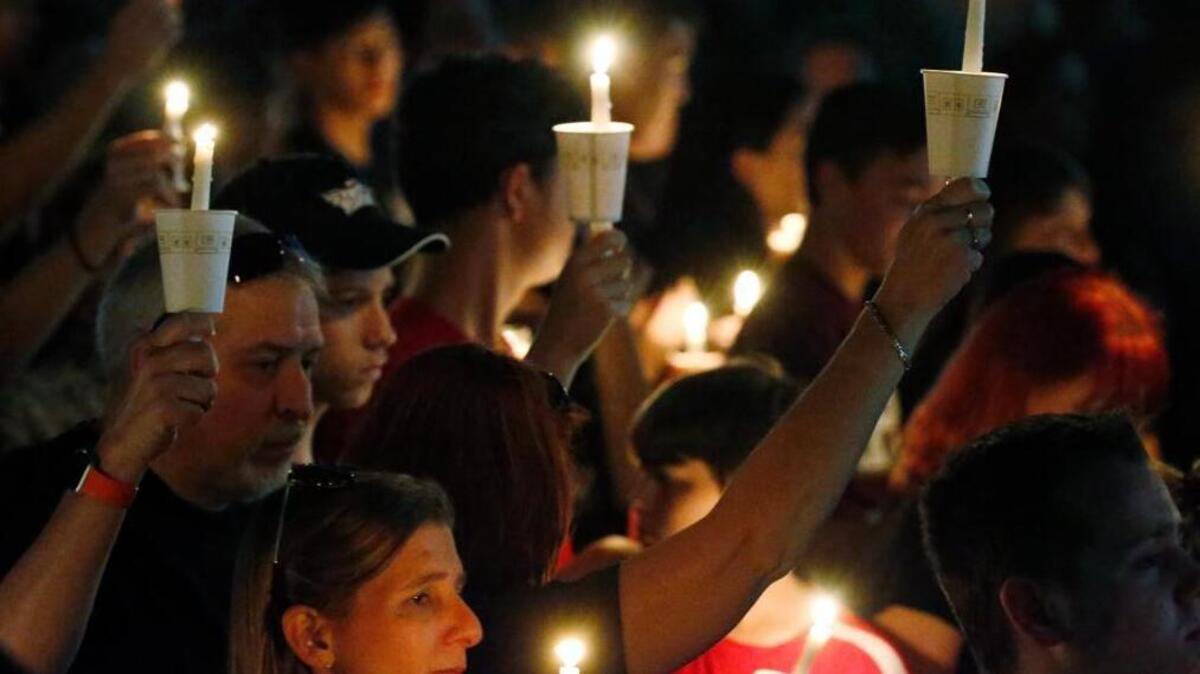 Attendees raise their candles at a candlelight vigil for the victims of the shooting at Marjory Stoneman Douglas High School, Thursday, Feb. 15, 2018, in Parkland, Fla. An orphaned 19-year-old with a troubled past and his own AR-15 rifle was charged with 17 counts of premeditated murder Thursday morning after being questioned for hours by state and federal authorities following the deadliest school shooting in the U.S. in five years.