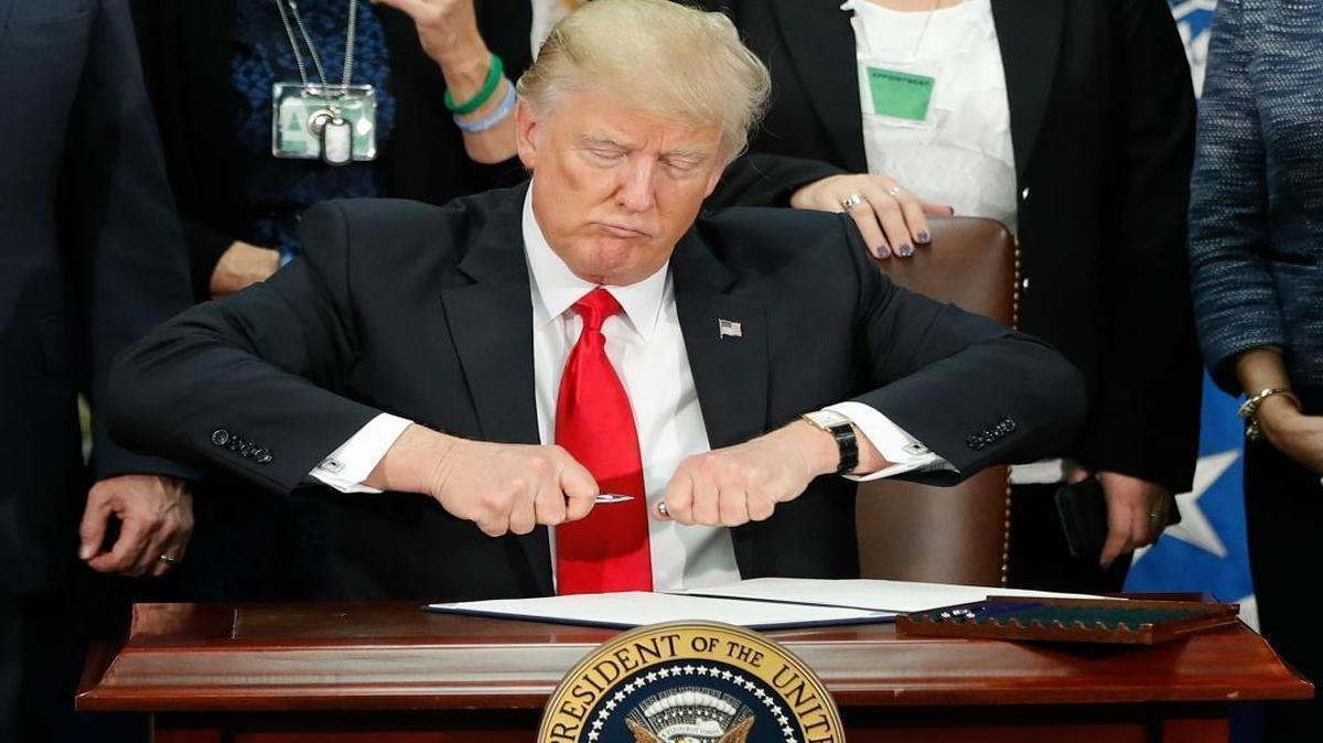 President Donald Trump takes the cap off a pen before signing executive order for immigration actions to build border wall during a visit to the Homeland Security Department in Washington, Wednesday, Jan. 25, 2017.