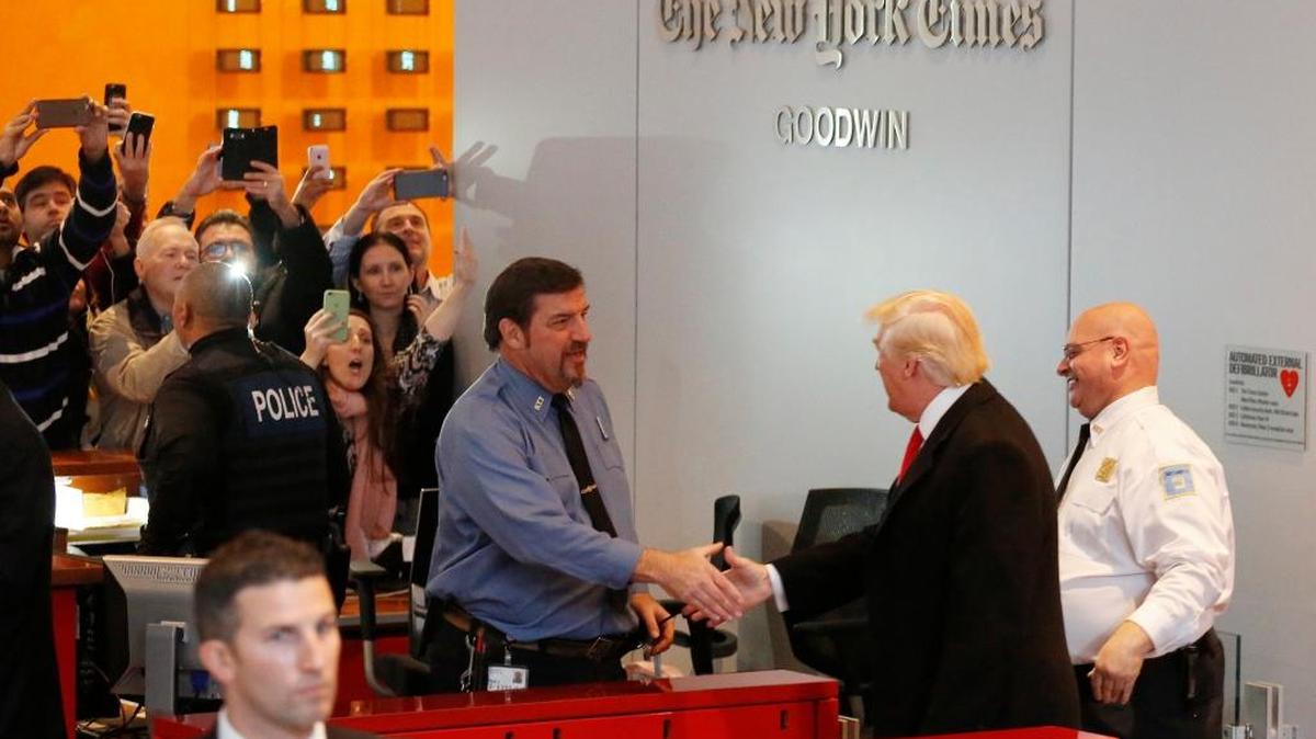 Onlookers watch as President-elect Donald Trump shakes hands with a security guard as he leaves the New York Times building following a meeting, Tuesday, Nov. 22, 2016, in New York.