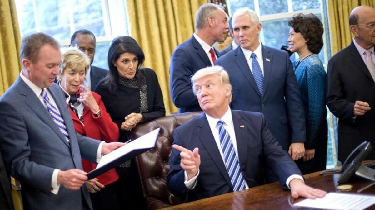 President Donald Trump looks over towards Budget Director Mick Mulvaney, left, after signing an executive order in the Oval Office of the White House in Washington, March 13, 2017
