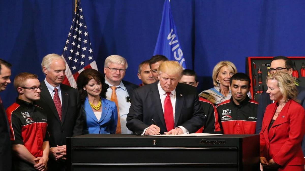 Surrounded by Snap-on workers and executives, President Donald Trump celebrates with them after signing a workplace executive order on Tuesday, April 18, 2017, at the Snap-on Inc. headquarters in Kenosha, Wis.