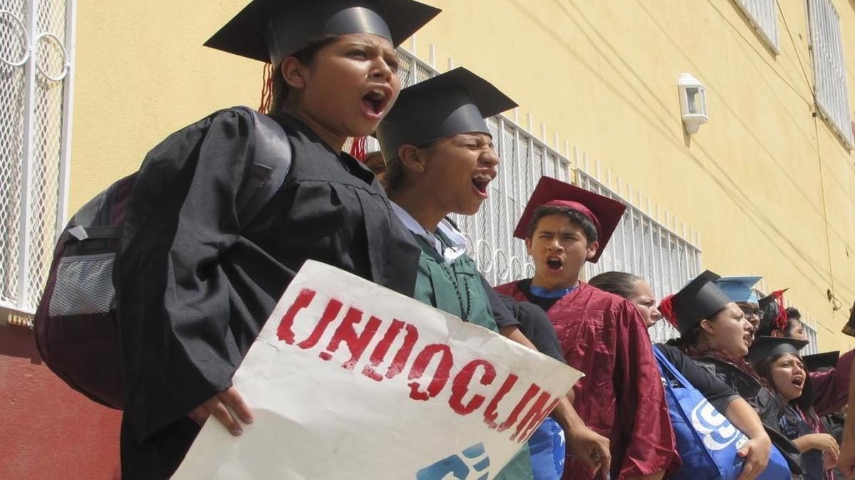 Wearing graduation-style caps and gowns, Mexican youth raised in the U.S, chant slogans outside a migrant shelter before crossing the international bridge from Nuevo Laredo, Mexico on Sept. 20, 2013. (AP Photo/Christopher Sherman, File)