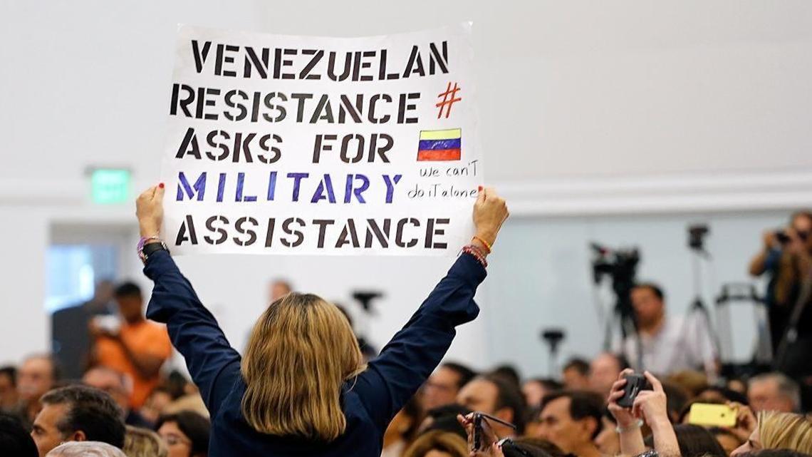 Woman holds up a sign as Vice President Mike Pence gives his remarks after meeting with several political exiles to highlight the Venezuelan crisis at Our Lady of Guadalupe Catholic Church, in Doral, Fla., on Wednesday, Aug. 23, 2017.
