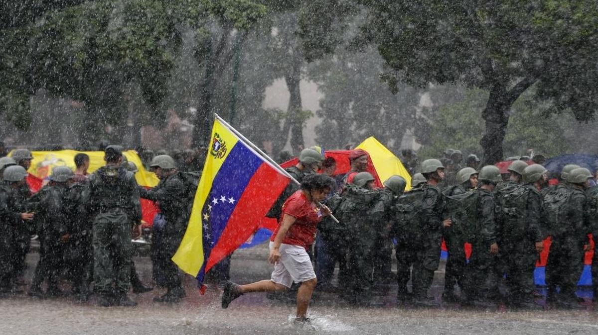 A follower of President Nicolas Maduro runs past a line of soldiers in Caracas, Venezuela, Saturday, Aug. 26, 2017.