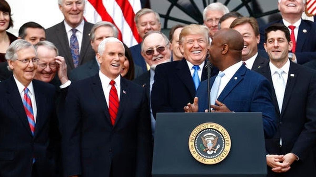 President Donald Trump smiles with Senate Majority leader Mitch mcConnell of Ky., Vice President Mike Pence and House Speaker Paul Ryan of Wis., as Sen. Tim Scott, R-S.C., speaks during a bill passage event on the South Lawn of the White House in Washington, Wednesday, Dec. 20, 2017, to acknowledge the final passage of tax overhaul legislation by Congress.