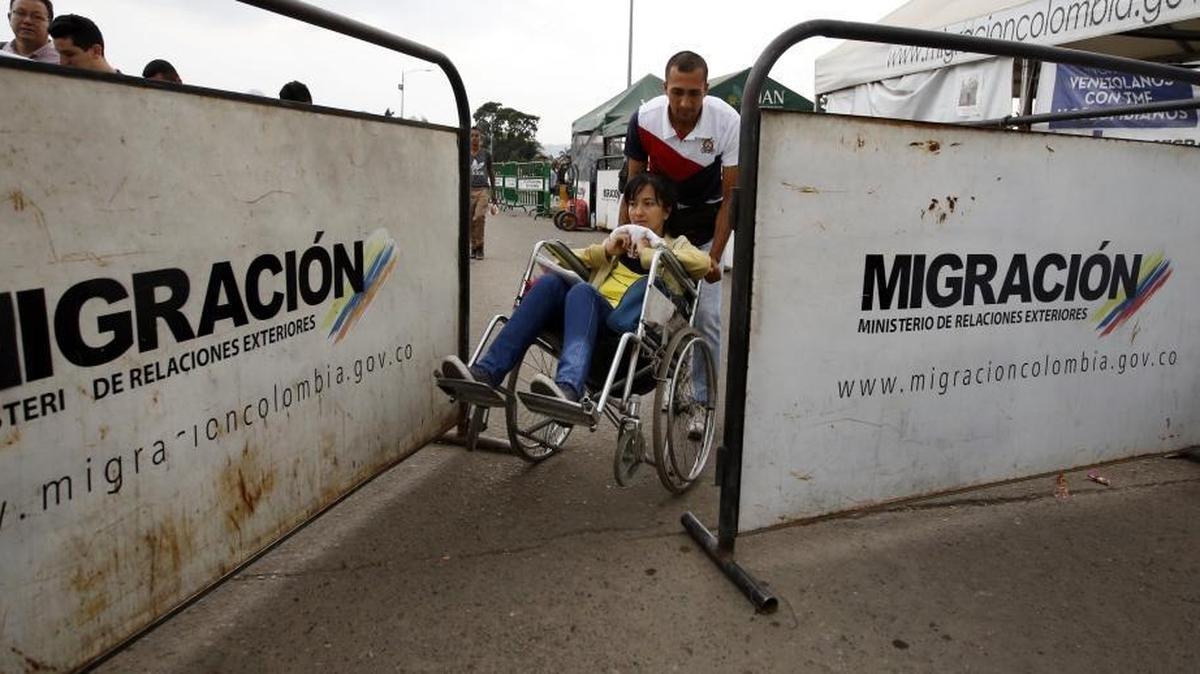 In this Feb. 22, 2018 photo, Venezuelan Nelson Gonzalez pushes his wife Grecia Sabala in a wheelchair across the international border back into Venezuela. Sabala returned after receiving permission to receive chemotherapy treatment in Cucuta, on the Colombian side of the border. Venezuela's health crisis is spilling into neighboring Colombia as thousands of migrants arrive in need of urgent medical attention.
