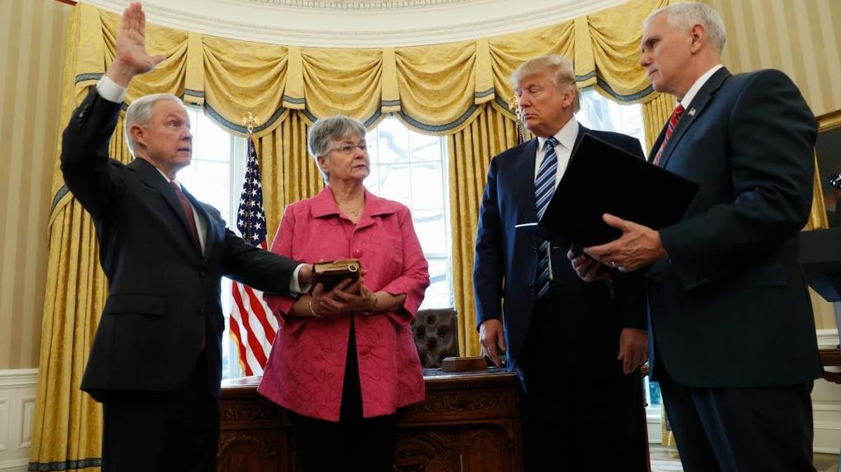 President Donald Trump watches as Vice President Mike Pence administers the oath of office to Attorney General Jeff Sessions, accompanied by his wife Mary on Thursday in the Oval Office of the White House in Washington.