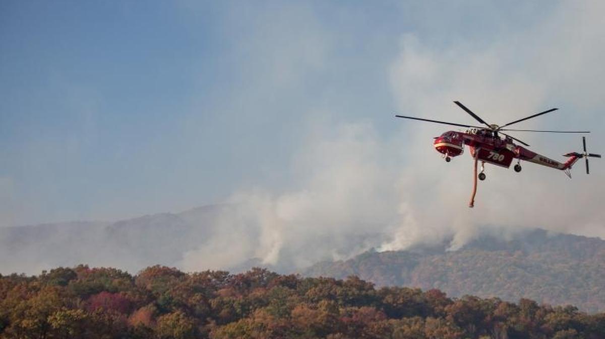 A firefighting helicopter fills its water tanks over Lake Lure on Wednesday, Nov. 17, 2016, as firefighters battled the Party Rock fire near Lake Lure and Chimney Rock in North Carolina.