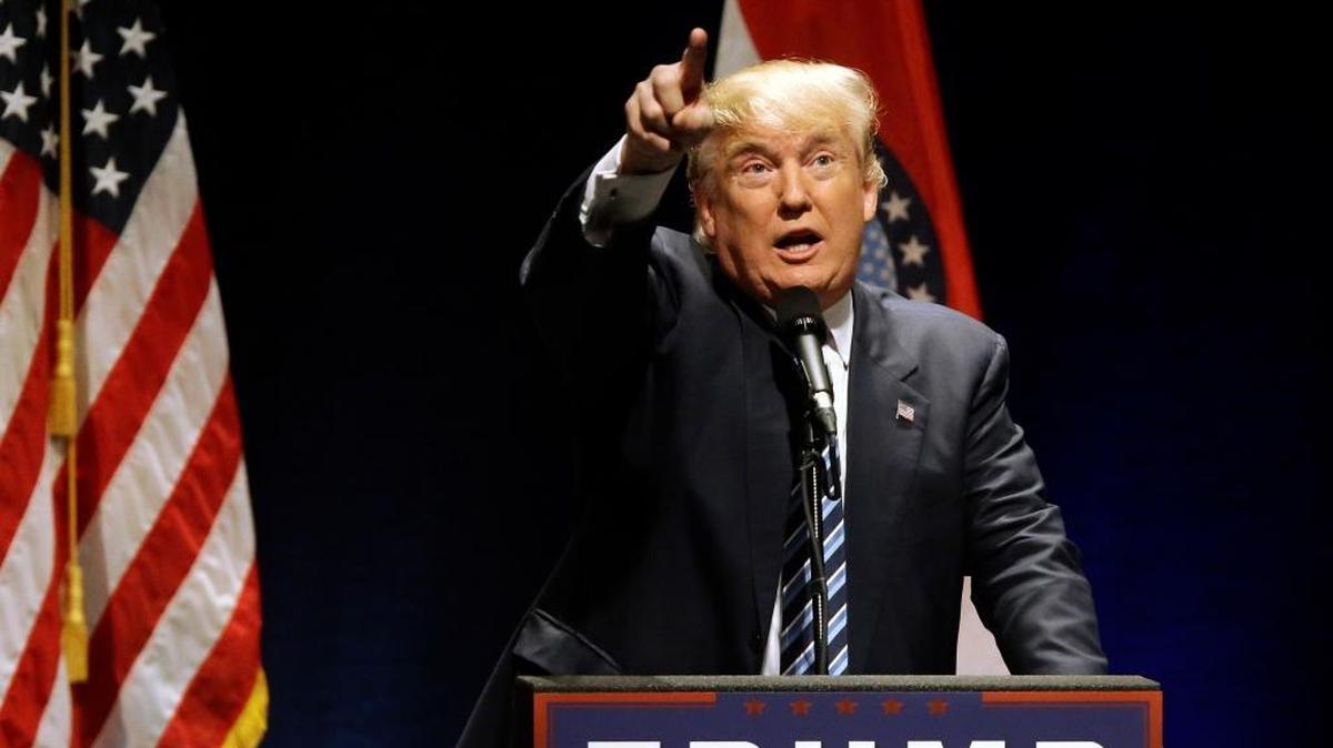 Donald Trump points to protesters who were causing a disturbance at a campaign rally in St. Louis. He has expressed sympathy for the anger some of his supporters feel regarding protesters.