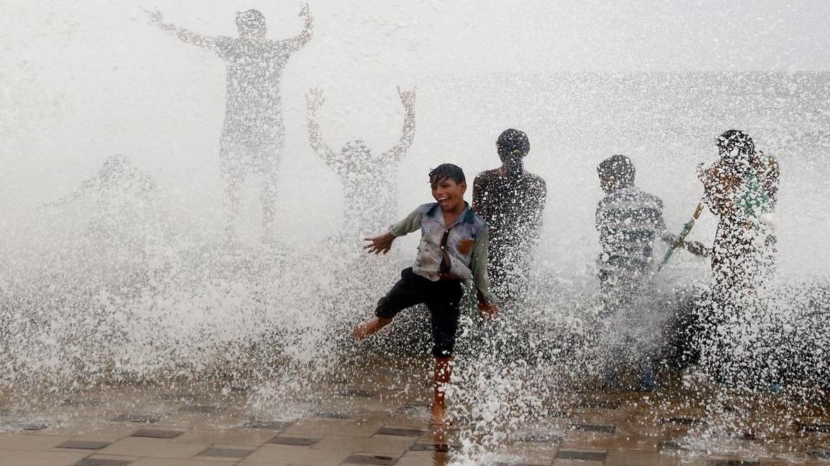Indians get drenched in waves hitting the shore during high tide at the Arabian Sea promenade in Mumbai, India, on Wednesday, July 6, 2016.