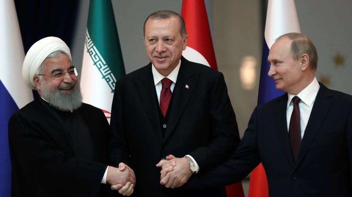 Iran's President Hassan Rouhani, left, Russia's President Vladimir Putin, right, and Turkey's President Recep Tayyip Erdogan lock hands during a group photo in Ankara, Turkey, Wednesday, April 4, 2018. The leaders of Russia, Iran and Turkey are meeting in the Turkish capital for talks on Syria's future.