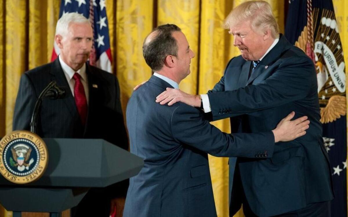 Trump Chief of Staff Reince Priebus (center), accompanied by Vice President Mike Pence, is embraced by President Donald Trump during a White House senior staff swearing-in ceremony in the East Room, Sunday, Jan. 22, 2017, in Washington.