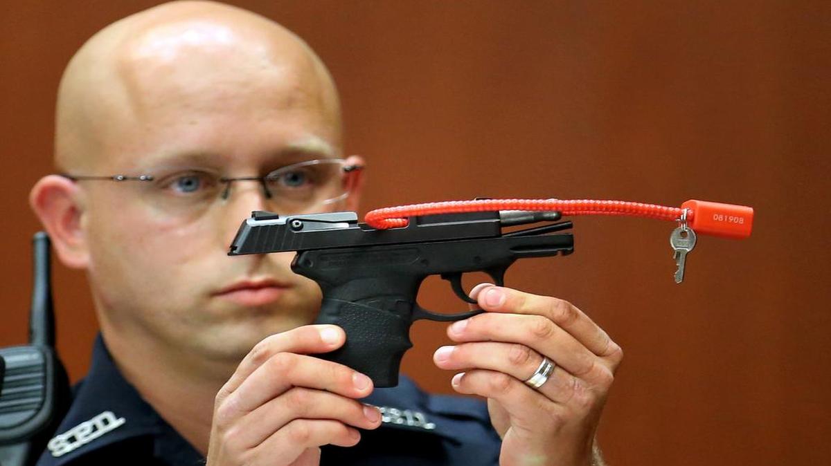A police officer holds up the gun that killed Trayvon Martin. It is being auctioned by the man who shot him, George Zimmerman.